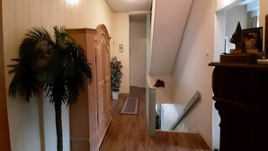 A hallway with wooden flooring, a wooden wardrobe, a potted plant, and a staircase leading to another level. - Ferienwohnung in Wildemann (Wildemann)