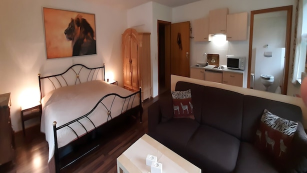 A bedroom with a bed, a bedside table, a nightstand, a wardrobe, a sofa, and a small table with two white objects. - Ferienwohnung in Wildemann (Wildemann)