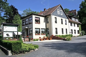 A two-story building with a balcony, a signboard, and outdoor seating.