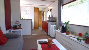 A compact living space with a kitchenette, a dining area, and a seating area with a sofa and a table. - Apartment in Meisberg with In-house Catering (Meisburg)