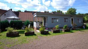 A single-story house with a porch, a satellite dish, and a gravel driveway. - Apartment in Meisberg with In-house Catering (Meisburg)