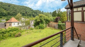 Um imóvel residencial com gramado, cerca de madeira e um prédio de tijolos com telhado ladrilhado.
