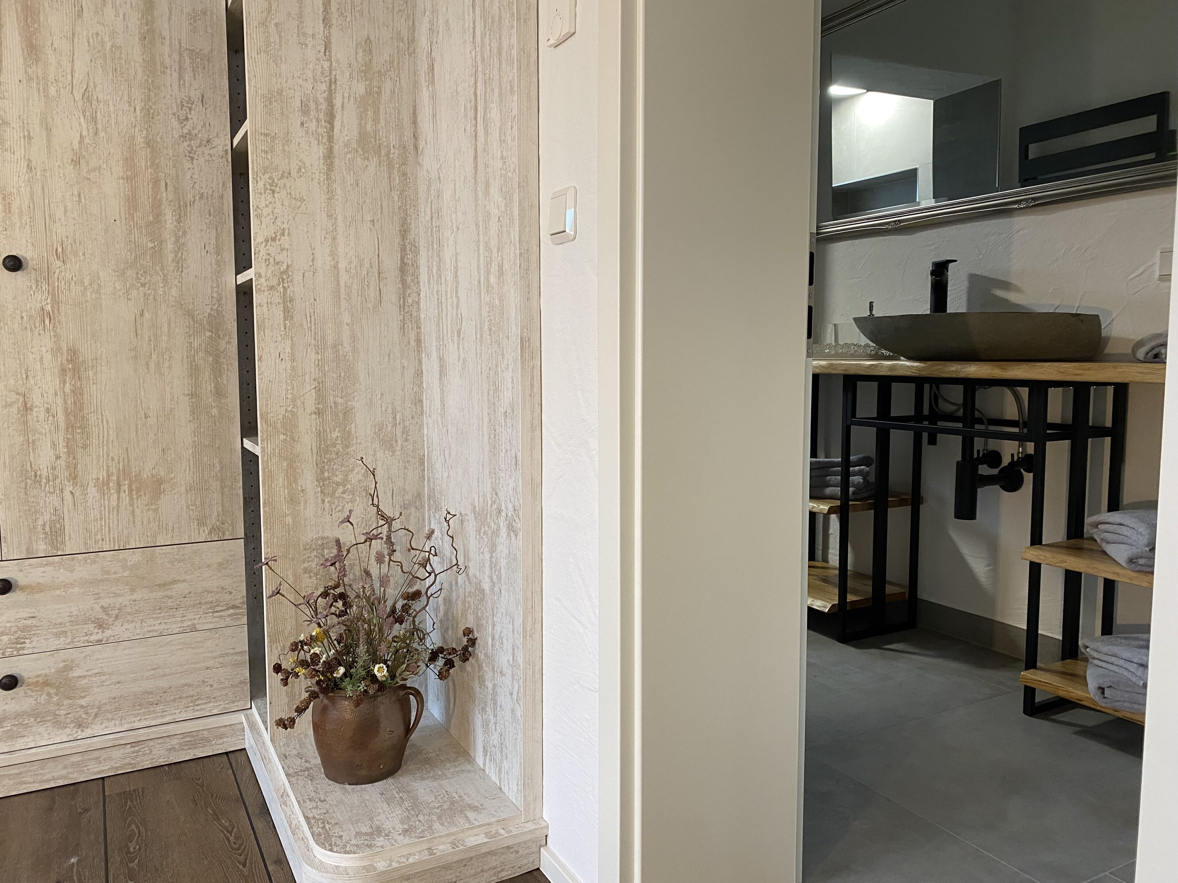 Un baño con tocador de madera, lavabo y espejo.