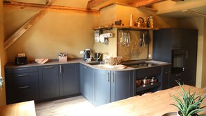 A kitchen with dark cabinets, a wooden countertop, and a hanging rack with utensils. - Haus Stenzinger (Burg (Spreewald))