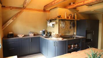 A kitchen with dark cabinets, a wooden countertop, and a hanging rack with utensils.