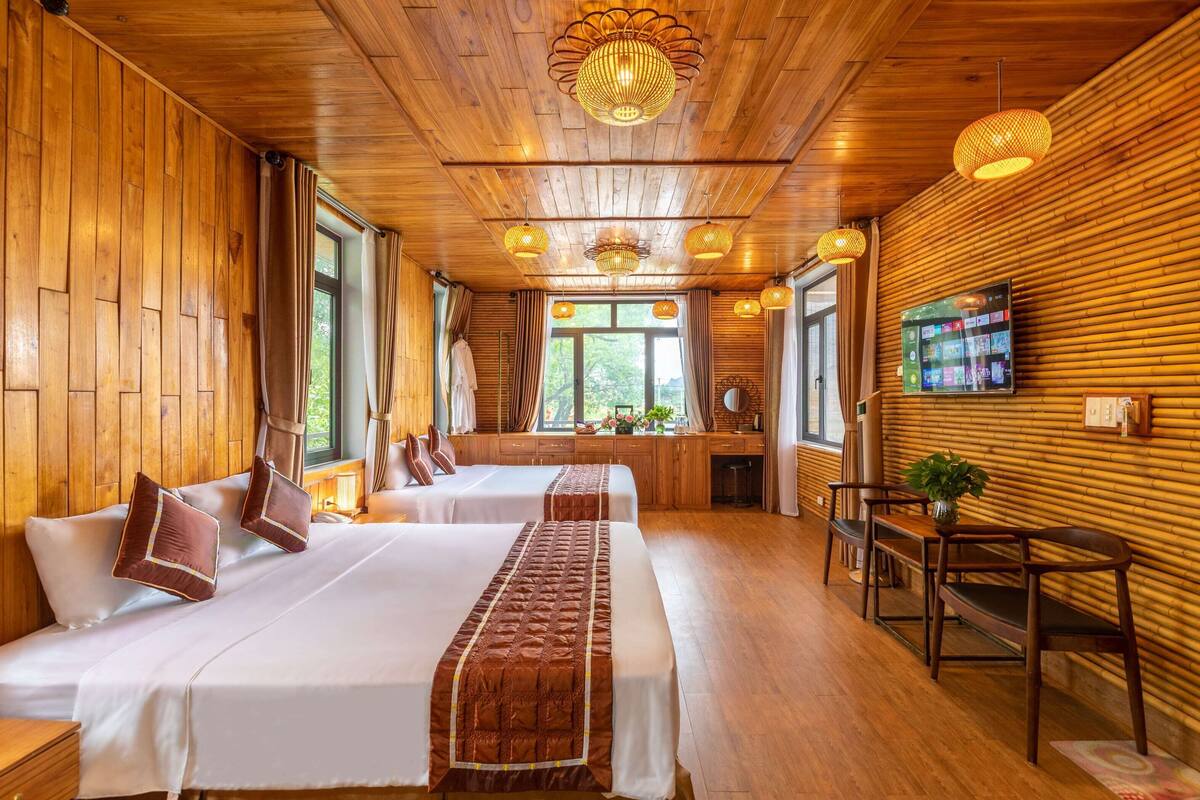 Une chambre à l’ambiance boisée, comprenant deux lits, un téléviseur et un coin salon.