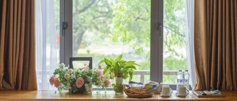 Een houten bureau met een bloemenvaas, een mand en een raam met gordijnen.