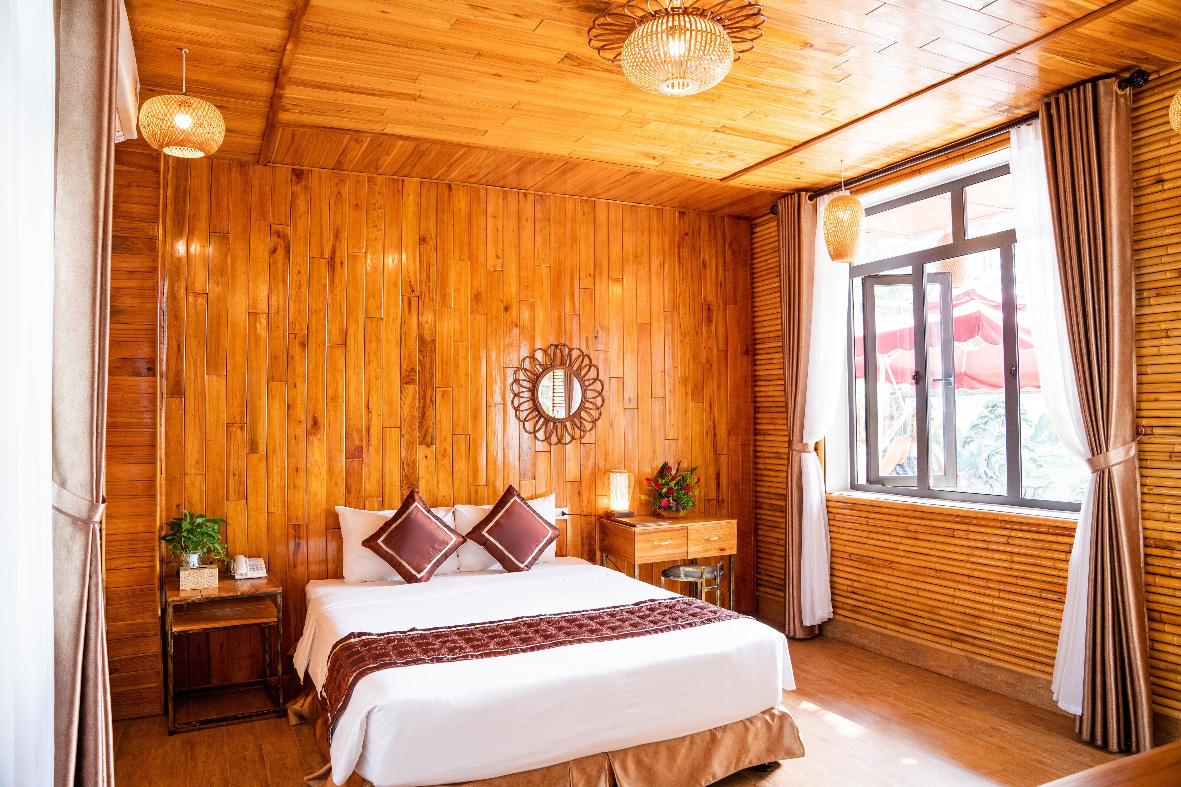 A wooden-paneled bedroom with a bed, bedside tables, a mirror, and a window with curtains.