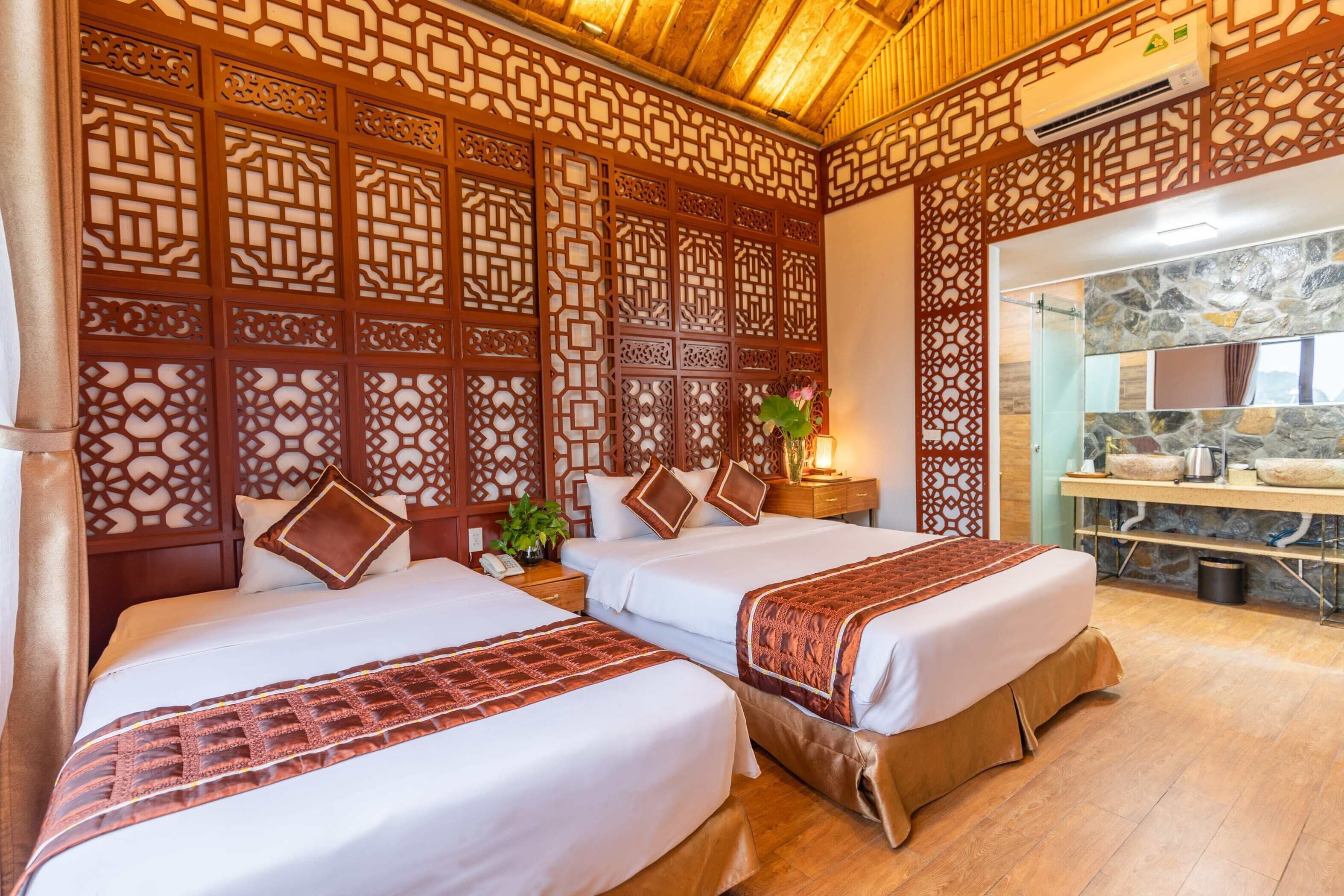 A hotel room with two beds, wooden paneling, a stone wall, and a small kitchenette.