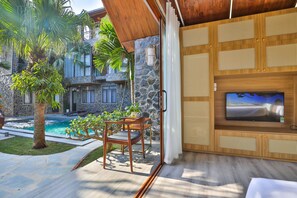 Ein moderner Außenbereich mit Pool, Steinmauern und einer Holz-Unterhaltungseinheit mit Fernseher.