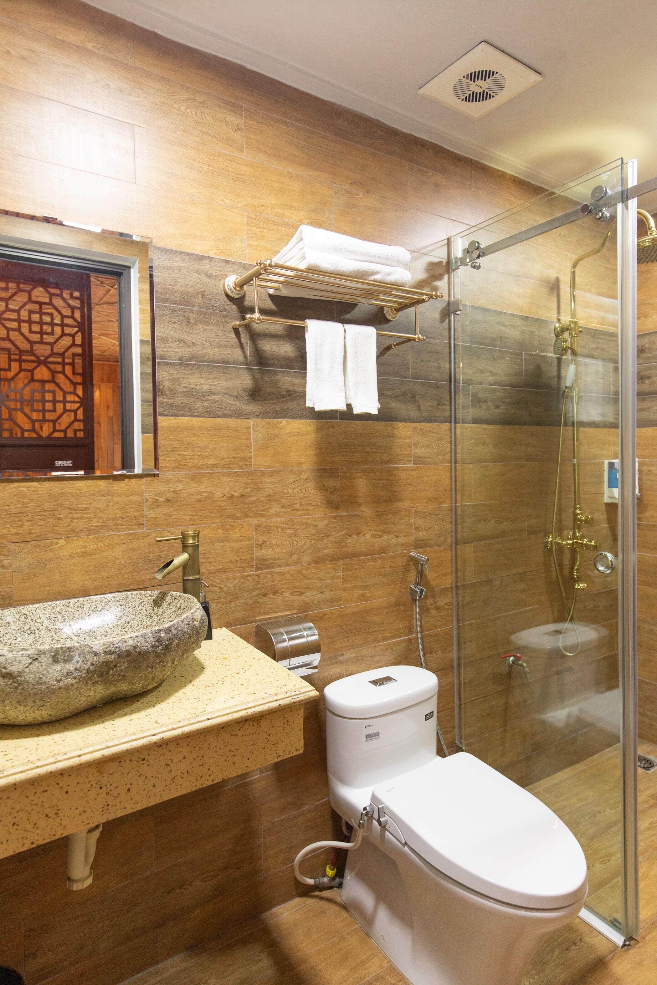 Ein Badezimmer mit einem Steintonne, einer weißen Toilette und einer Duschkabine.