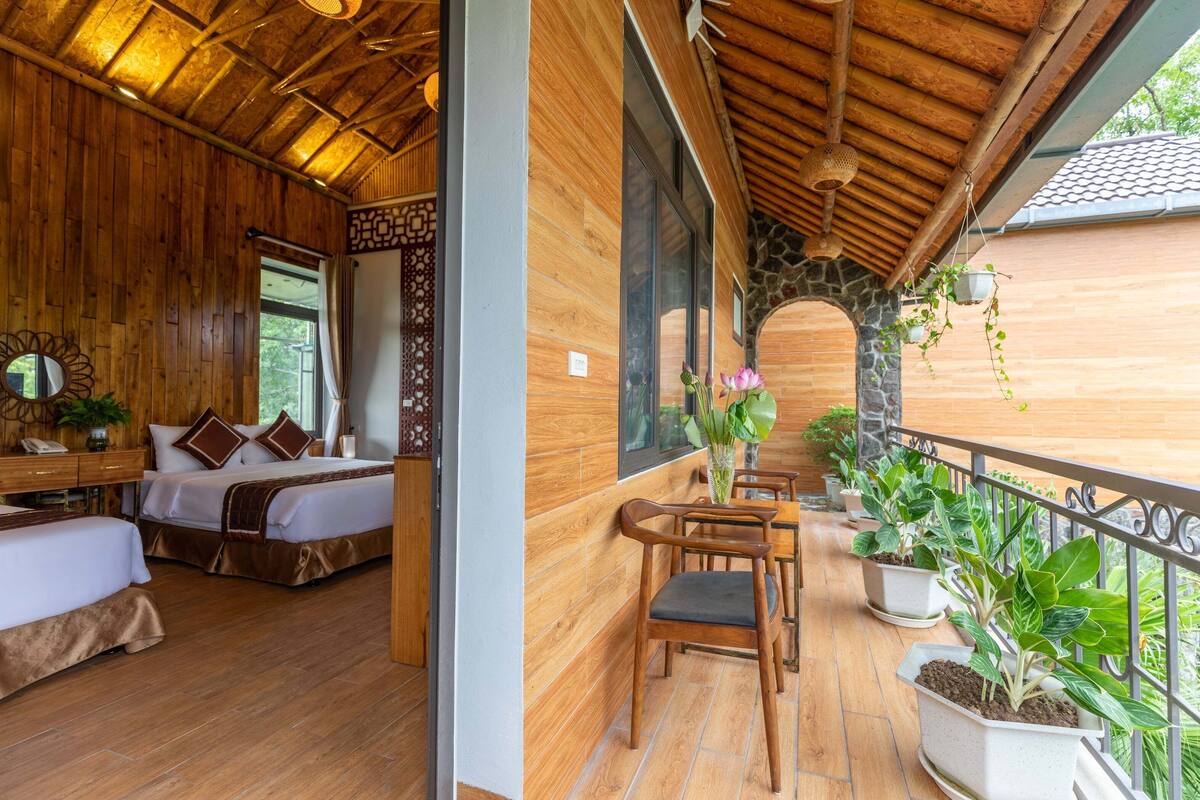 Un intérieur en bois avec un balcon, des lits et des plantes en pot.