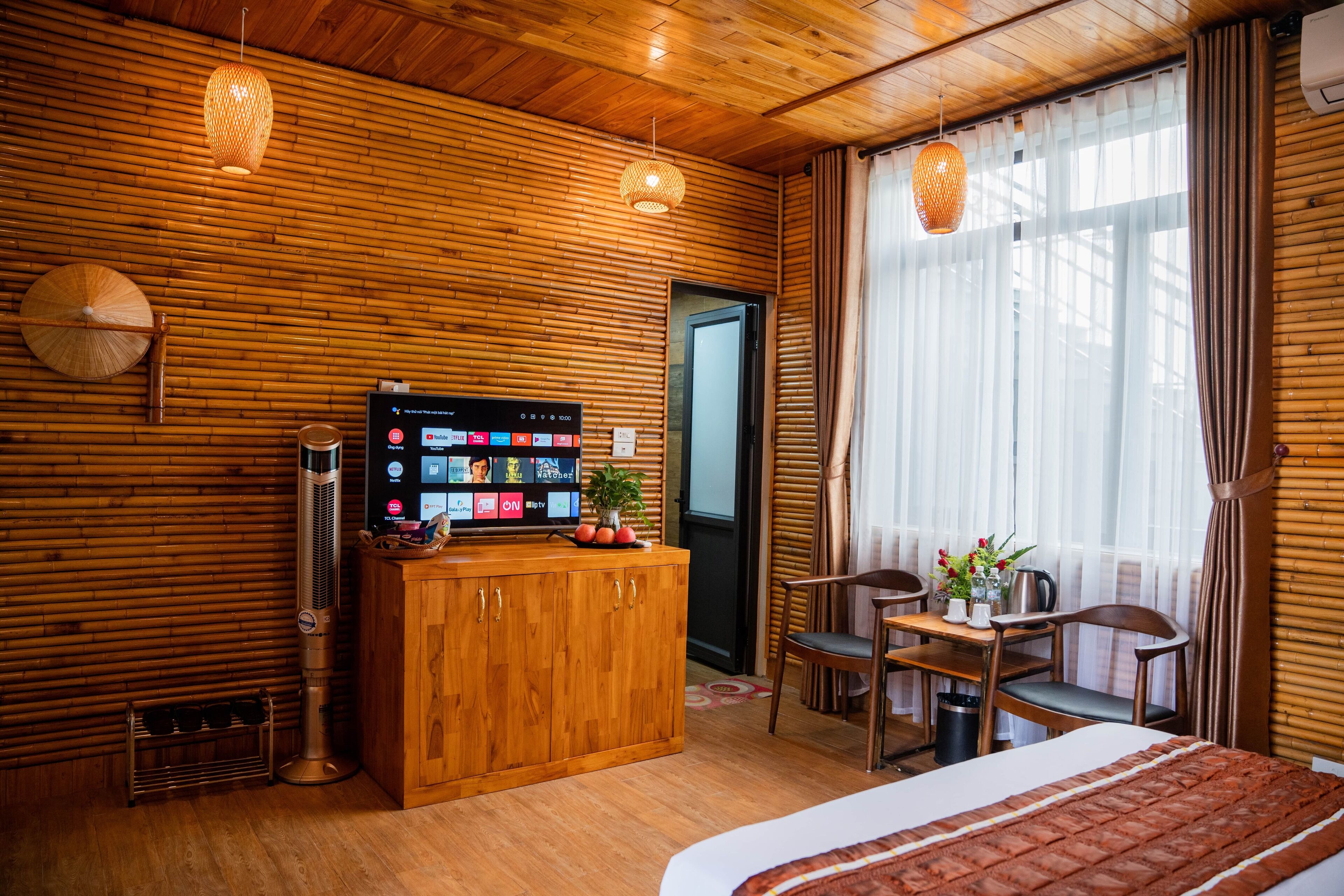 A wooden-paneled room with a bed, a desk, and a television displaying a video call.