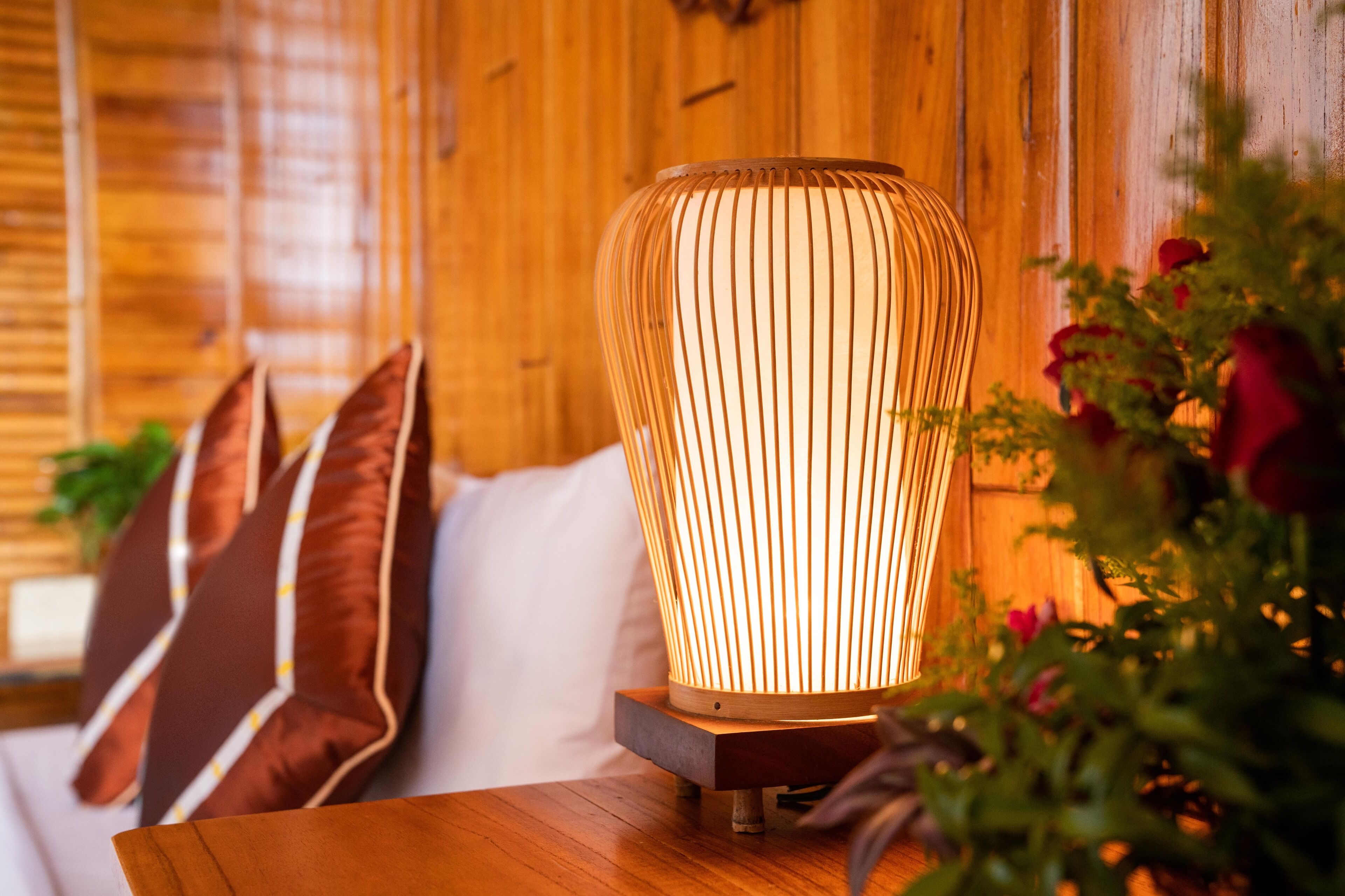 A wooden table with a lamp, a sofa with cushions, and a plant.