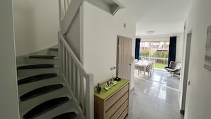 Una escalera conduce a una habitación con un aparador de madera y un comedor con mesa y sillas.