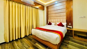 A hotel room with a large bed, wooden headboard, and a ceiling fan. - Hotel Ultra International (Siddharthanagar)