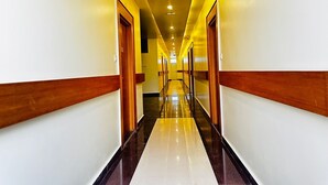 A long, narrow hotel corridor with white walls and wooden trim. - Hotel Ultra International (Siddharthanagar)