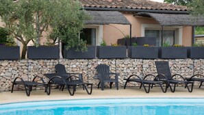 Uma área de piscina com espreguiçadeiras e uma parede de pedra.
