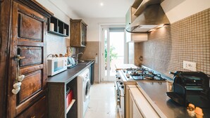 A modern kitchen with wooden cabinets, a stainless steel range, and a tiled backsplash. - Bright studio in Trastevere/ ponte Testaccio (Roma)