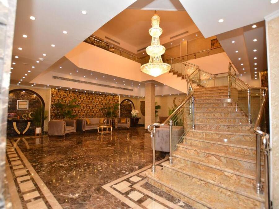 A spacious lobby with a marble floor, a grand staircase, and a chandelier.