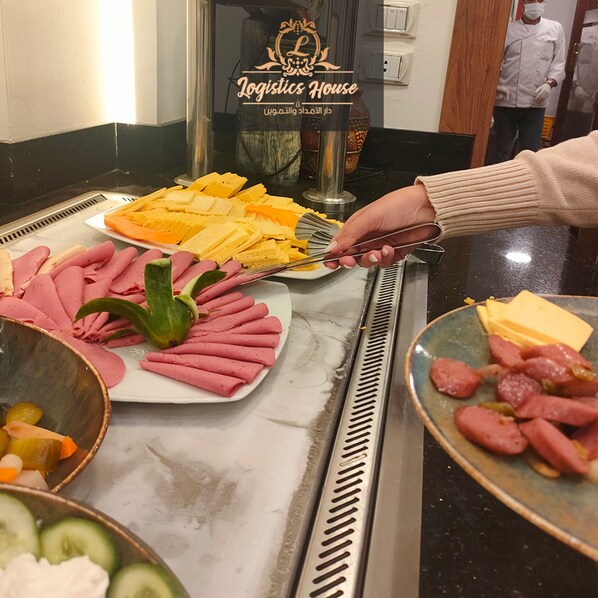 A buffet counter with various food items including sliced cheese, cured meats, and vegetables. - logistic hotel city stars (Cairo)