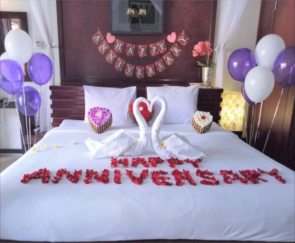 Romantic getaway awaits with a plush bed, swan-shaped pillows, and a heartfelt floral arrangement.