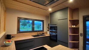 Eine moderne Küche mit großem Fenster, einem eingebauten Backofen und Holzschränken.
