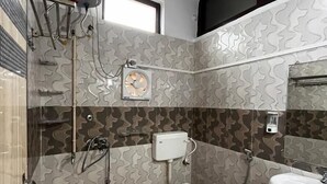 A bathroom with a toilet, sink, shower, and a red bucket. - Sewadham Training Centre (Phulpur)