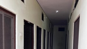A long, narrow hallway with doors on both sides and a red-tiled floor. - Sewadham Training Centre (Phulpur)