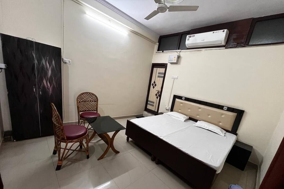 Quarto com cama, cadeira, mesa e ar condicionado na parede.