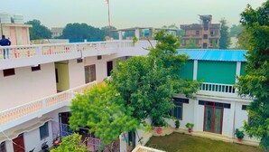 A multi-story building with balconies, a courtyard, and potted plants. - Sewadham Training Centre (Phulpur)