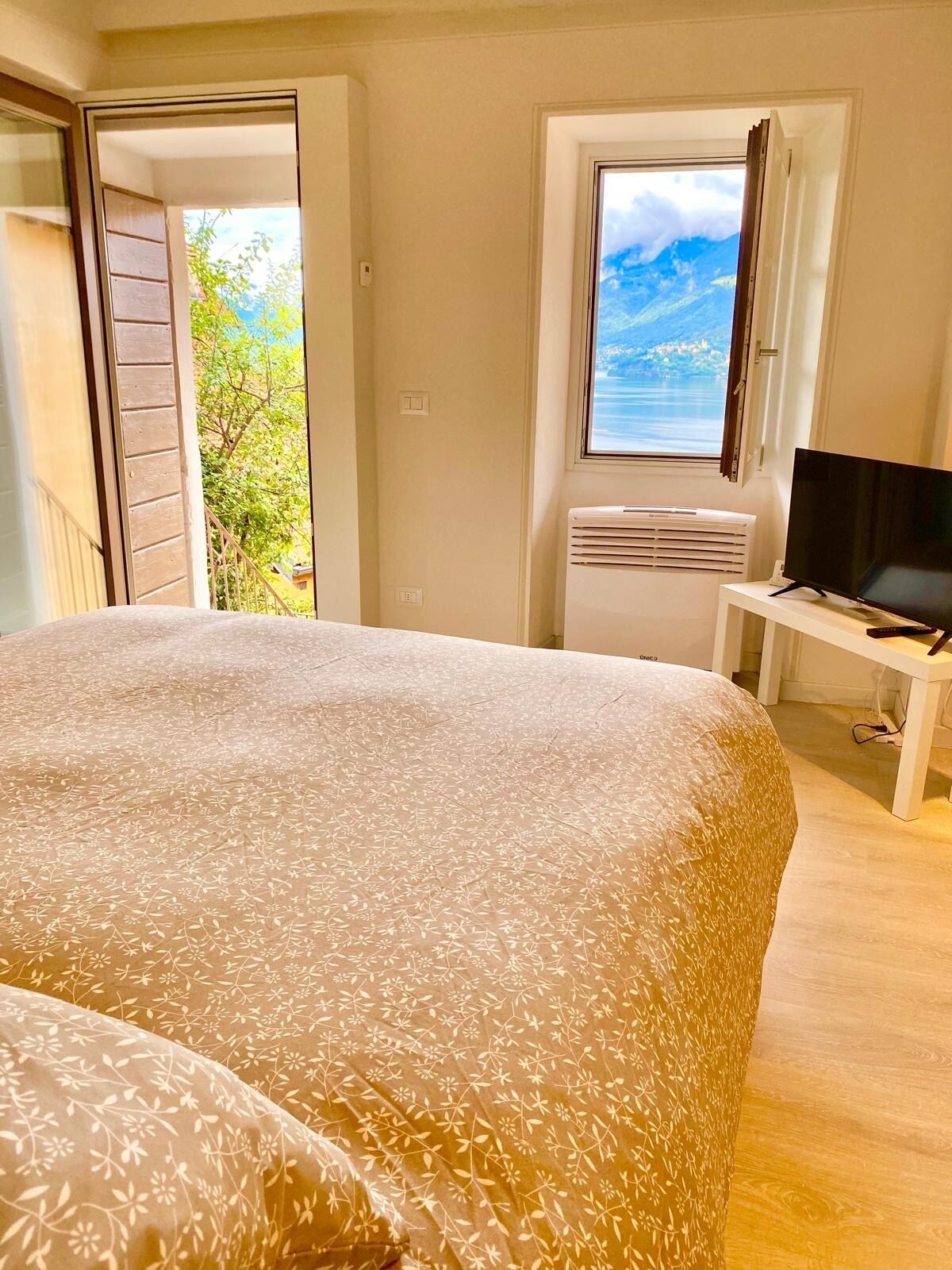 Ein Schlafzimmer mit einem Bett, einem Fernseher und einem Fenster mit Blick ins Freie.