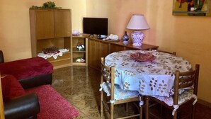 A cozy room with a wooden cabinet, a television, a table with a floral tablecloth, and a chair. - Delightful little room Near Colosseum!!! (Roma)