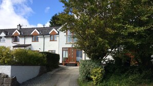 A residential street with houses, a gravel driveway, and greenery. - Spacious Ty Adeiladwr Cwch, with stunning mountain views near Red Wharf Bay (Llanddona)