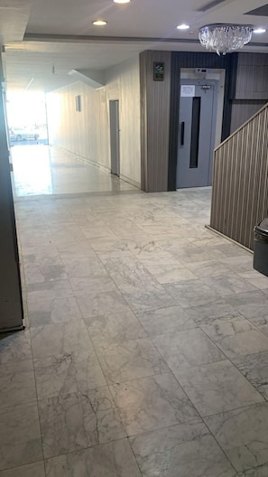 A hallway with a marble floor, a chandelier, and a door with a sign.