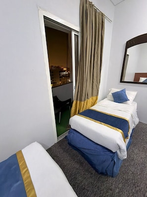 Habitación de hotel con cama, una silla, un espejo y vista a la ciudad a través de la ventana.