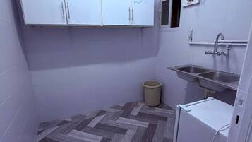 Una cocina compacta con armarios blancos, un lavamanos, un refrigerador pequeño y un piso con ziguezague.