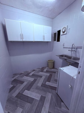 Una cocina compacta con armarios blancos, un lavamanos, un refrigerador pequeño y un piso con ziguezague.