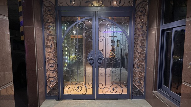 A double door entrance with intricate metalwork, a tiled floor, and a hanging light fixture. - Equus Motel (Jincheon)