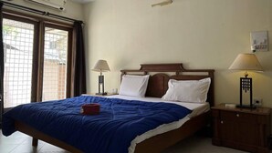 A hotel room with a bed, two bedside lamps, an air conditioner, and a window with curtains. - Brham Store and Residency Brunton Road  (Bengaluru)