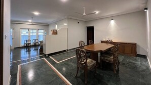 A spacious room with a dining table and chairs, a ceiling fan, and a kitchen area. - Brham Store and Residency Brunton Road  (Bengaluru)