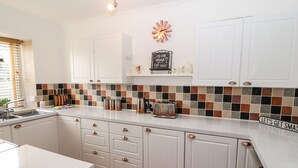 Een moderne keuken met witte kastjes, een betegelde spatwand en een aanrecht met een broodrooster en koffiezetapparaat.