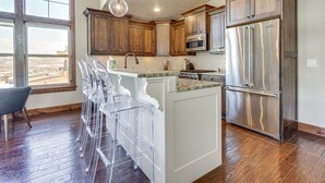 A kitchen with wooden cabinets, stainless steel appliances, and a large island with bar stools. - All-season Heber City Condo w/ Stunning Views! (Heber City)