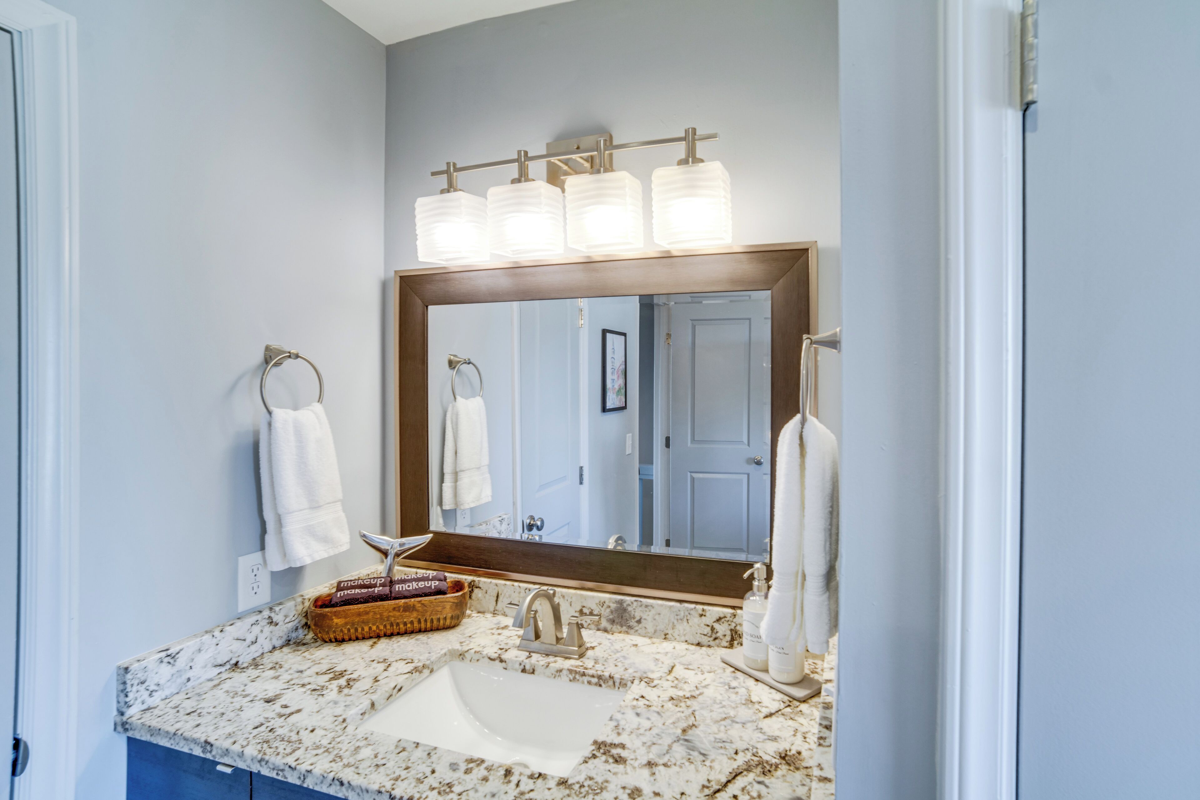 A bathroom with a marble sink, a large mirror, and a towel rack.
