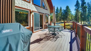 A wooden deck with a table and chairs, a grill, and a view of a forest. - Quiet Leadville Home on 3 Acres w/ Gas Grill! (Leadville)