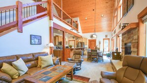 A spacious living area with a high ceiling, wooden staircase, and a kitchen in the background. - Quiet Leadville Home on 3 Acres w/ Gas Grill! (Leadville)