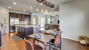 Una cocina moderna con una isla central, electrodomésticos de acero inoxidable e iluminación colgante.