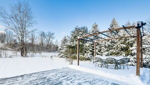 Lumipeitteinen terassi, jossa on puinen pergola ja ulkokalusteet.