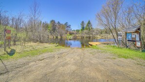 A dirt path leading to a small cabin by a lake with a picnic table and informational signs. - Townsend Cottage on UTV & Snowmobile Trail! (Townsend)