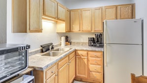 A kitchen with wooden cabinets, a built-in oven, a refrigerator, and a coffee maker. - Townsend Cottage on UTV & Snowmobile Trail! (Townsend)